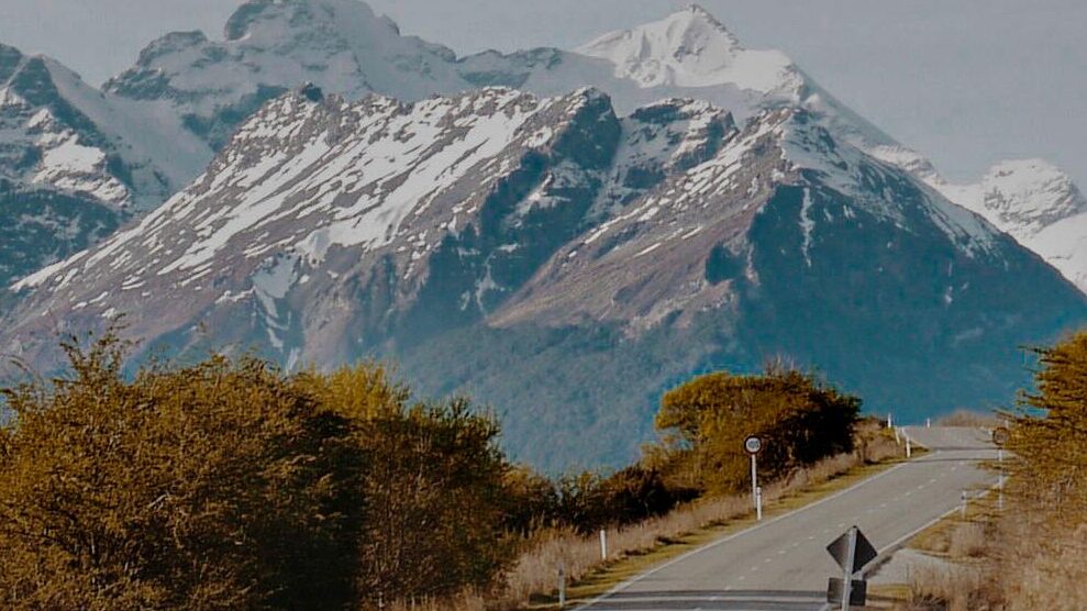 A winding road leading to snow-capped mountains under a star-filled sky in a serene outdoor setting.